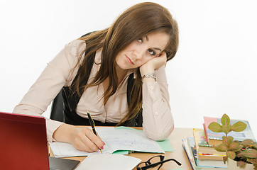 Image showing Tired teacher checks students notebooks