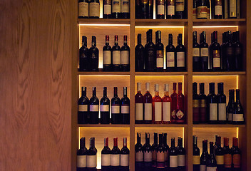 Image showing Wine bottles on a wooden shelf.