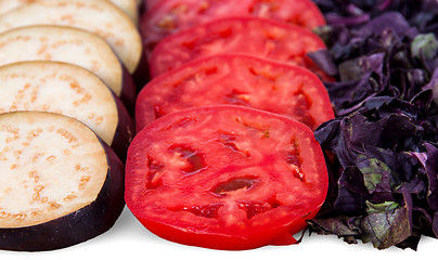 Image showing Sliced eggplant tomato and basil leaves