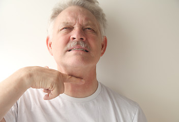 Image showing Senior man gestures with finger across throat. 