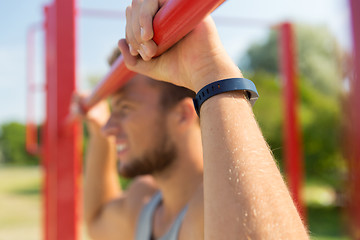 Image showing young man exercising on horizontal bar outdoors