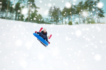 Image showing happy teenage girl sliding down on snow tube