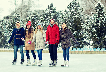 Image showing happy friends ice skating on rink outdoors