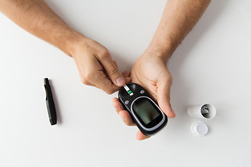 Image showing close up of man checking blood sugar by glucometer