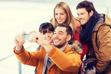 Image showing happy friends with camera on skating rink