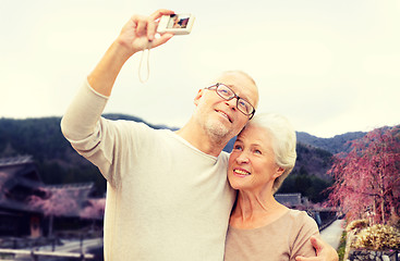 Image showing senior couple with camera over asian village