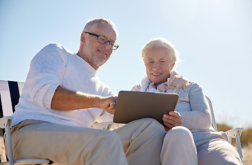 Image showing happy senior couple with tablet pc on summer beach