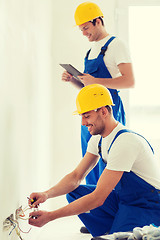 Image showing builders with tablet pc and fixing wiring indoors