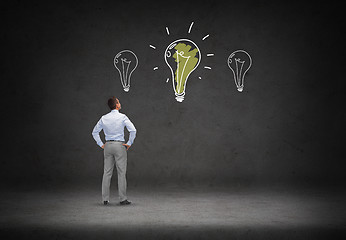 Image showing businessman looking at lighting bulb doodles