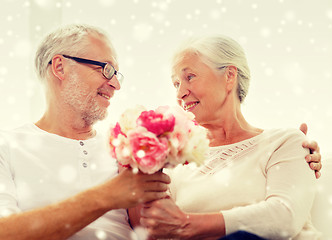 Image showing happy senior couple with bunch of flowers at home