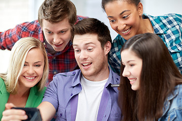 Image showing group of happy students with smartphone at school