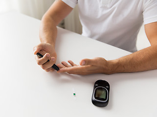 Image showing close up of man checking blood sugar by glucometer