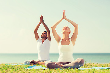 Image showing smiling couple making yoga exercises outdoors