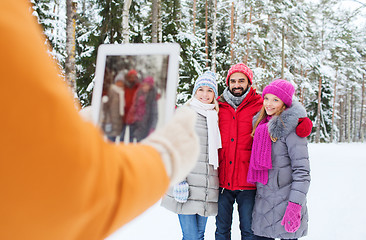 Image showing smiling friends with tablet pc in winter forest