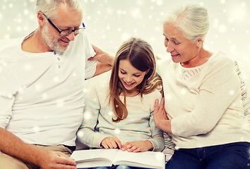 Image showing smiling family with book at home