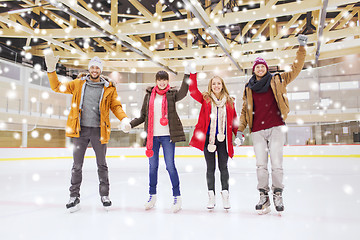 Image showing happy friends waving hands on skating rink