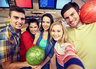 Image showing happy friends taking selfie in bowling club