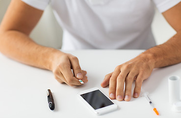 Image showing close up of man with smartphone making blood test