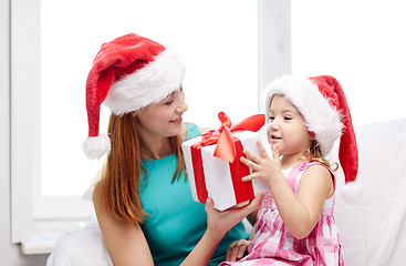 Image showing happy mother and child in santa hats with gift box