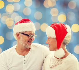 Image showing happy senior couple in santa helper hats