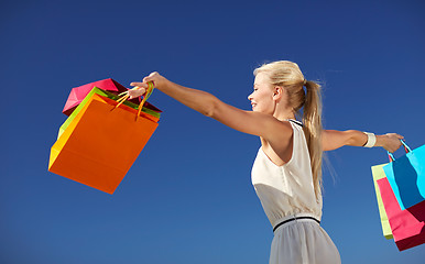 Image showing smiling woman with shopping bag rising hands