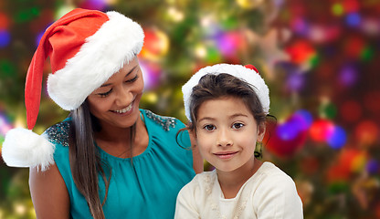 Image showing happy mother and little girl in santa hats at home