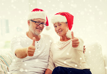 Image showing happy senior couple in santa helper hats at home