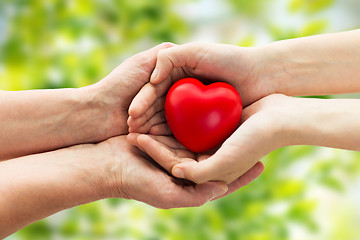Image showing senior and young woman hands holding red heart