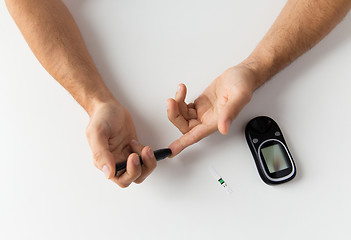 Image showing close up of man checking blood sugar by glucometer