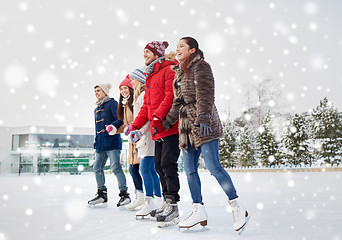 Image showing happy friends ice skating on rink outdoors