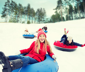 Image showing group of happy friends sliding down on snow tubes