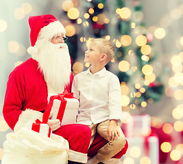 Image showing smiling little boy with santa claus and gifts