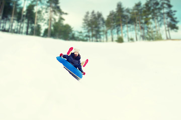 Image showing happy teenage girl sliding down on snow tube