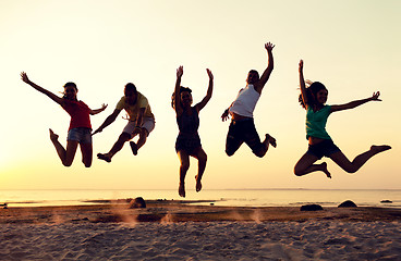 Image showing smiling friends dancing and jumping on beach