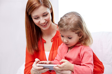 Image showing happy mother and daughter with smartphone at home