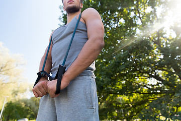 Image showing young man exercising with expander in summer park