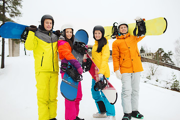 Image showing happy friends in helmets with snowboards outdoors