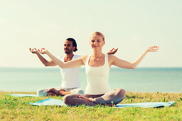 Image showing smiling couple making yoga exercises outdoors