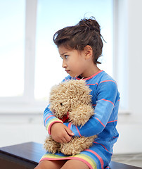 Image showing sad little girl with teddy bear toy at home