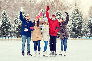 Image showing happy friends ice skating on rink outdoors