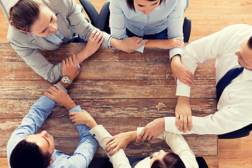 Image showing close up of business team holding hands at table