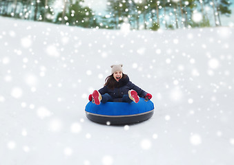 Image showing happy teenage girl sliding down on snow tube