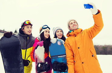 Image showing happy friends with snowboards and smartphone