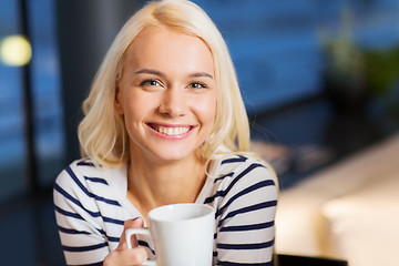 Image showing smiling young woman drinking coffee at cafe