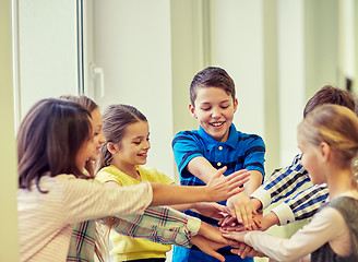 Image showing group of smiling school kids putting hands on top