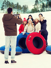 Image showing group of smiling friends with snow tubes