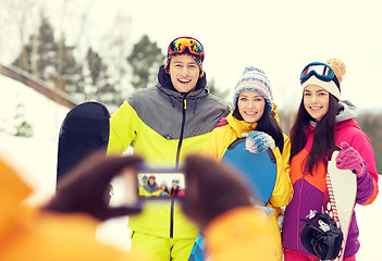 Image showing happy friends with snowboards and smartphone