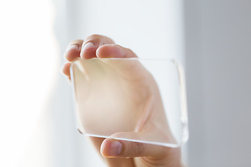 Image showing close up of male hand with transparent smartphone