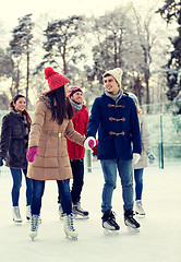 Image showing happy friends ice skating on rink outdoors