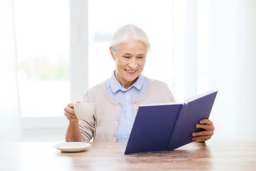 Image showing happy smiling senior woman reading book at home